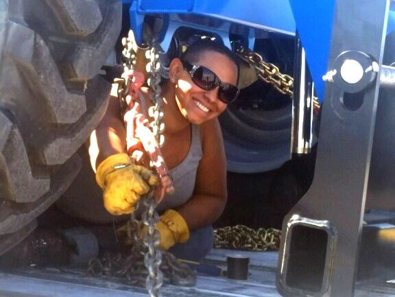 Female flatbed driver securing a load with chains