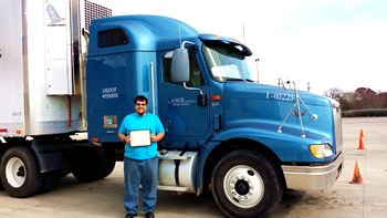 truck driving school graduate in front of his truck with diploma