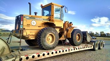 A flatbed trailer carrying a front heavy machinery