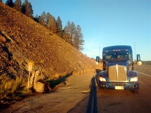 Blue Kenworth tractor trailer parked on the side of the road at sunset